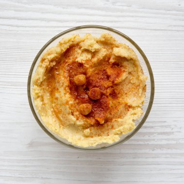 Humus nohut ile kırmızı biber ve zeytinyağı bir beyaz tahta yüzey, en iyi görünümde kase. Yukarıdan, ek yük düz lay.