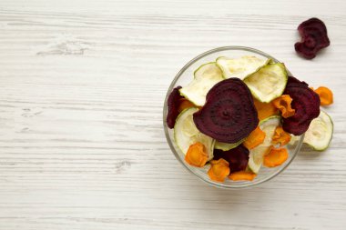 Sebze cips Beyaz ahşap masa, havai görünümü üzerinde tam kase. Kopya alanı.