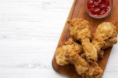 Üstten görünüm, Beyaz ahşap zemin üzerinde ahşap tahta üzerinde soslu kızarmış tavuk sopaları. Tepegöz, lay, yukarıdan düz. Kopya alanı.