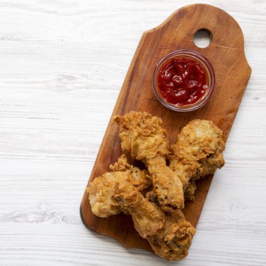 Düz beyaz ahşap masa üzerinde ahşap tahta üzerinde soslu kızarmış tavuk sopaları yatıyordu. Tepegöz, yukarıdan lay, düz. 