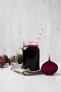 Güler yüzlü, yan görünümü ile yarıya pancar. Beyaz ahşap zemin.