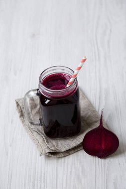 Cam kavanoz pancar güler yüzlü beyaz ahşap arka planda, yüksek açı.