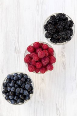 Üç kase çilek içeren: yaban mersini, böğürtlen, ahududu. Sağlıklı beslenme ve diyet. Yukarıdan, tepegöz, görünümü en iyi..