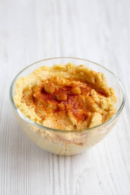 Leblebi, kırmızı biber, zeytin yağı Beyaz ahşap bir masa yan görünüm üzerinde humus kase. Portre.