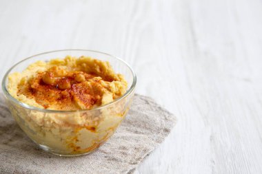 Leblebi, kırmızı biber, zeytin yağı Beyaz ahşap arka plan, yan görünüm üzerinde humus kase. Boşluk ve metin alanı Kopyala.