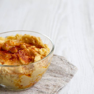 Leblebi, kırmızı biber, zeytin yağı Beyaz ahşap yüzey, yan görünüm üzerinde humus kase. 