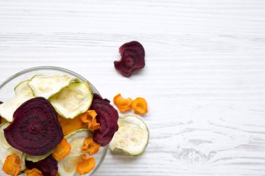 Sebze cips Beyaz ahşap arka plan, havai görünümü üzerinde tam kase. Metin için yer.