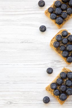 Fıstık ezmesi, yaban mersini ve beyaz ahşap bir masa üstten görünüm üzerinde chia tohum ile Vegan tost. Sağlıklı beslenme. Yukarıdan Lay, düz. Metin için yer.