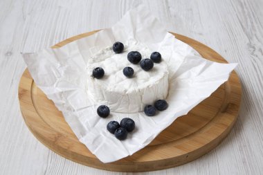 Bambu kağıda camembert peyniri Beyaz ahşap masa, düşük açılı üzerinde kurulu. Yiyecek şarap.