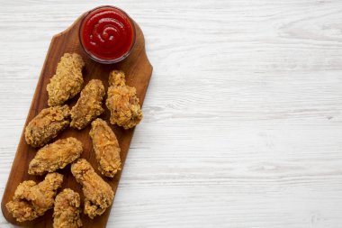 Rustik ahşap tahta ile beyaz ahşap arka plan, havai görünümü üzerinde kırmızı biber soslu tavuk kanatları. Kopya alanı.