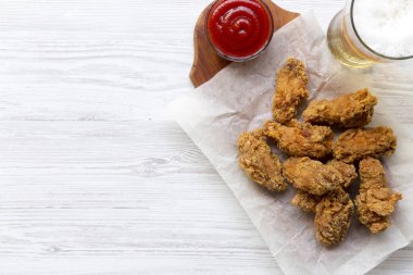 Soslu tavuk kanatları, Beyaz ahşap bir masa havai görünümü üzerinde soğuk bira. Yukarıdan Lay, düz. Kopya alanı.