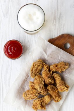 Soslu kızarmış tavuk kanatları, Beyaz ahşap bir masa üstten görünüm üzerinde soğuk bira. Yukarıda, ek yükü. Portre.