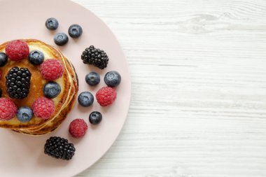 Beyaz ahşap arka plan, üstten görünüm üzerinde pembe bir plaka üzerinde çilek ile krep. Kopya alanı.