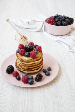 Krep çilek ve yan görünüm pembe bir tabakta bal ile. Beyaz ahşap masa.