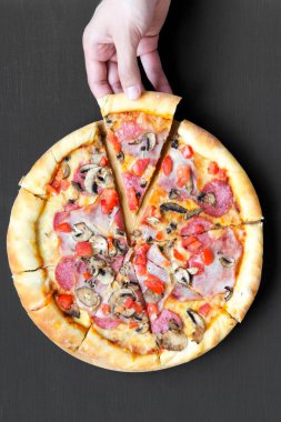 El dilim taze pişmiş pizza alır. Düz yatıyordu, genel gider, en iyi görünüm. Portre. Siyah arka plan.