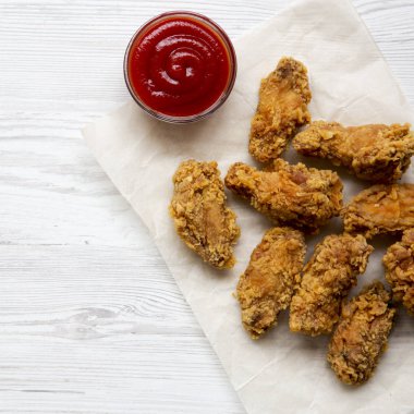 Beyaz ahşap bir masa üstten görünüm üzerinde soslu kızarmış tavuk kanatları. Yukarıda, ek yükü. Portre.