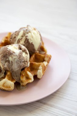 Beyaz ahşap yüzey, yan görünüm üzerinde pembe plaka üzerinde limon-çikolata dondurma ile geleneksel Belçika waffle. Portre. 