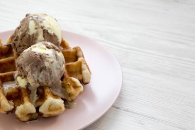 Beyaz ahşap arka plan, yan görünüm üzerinde pembe plaka üzerinde dondurma ile geleneksel Belçika waffle. Portre. Kopya alanı.