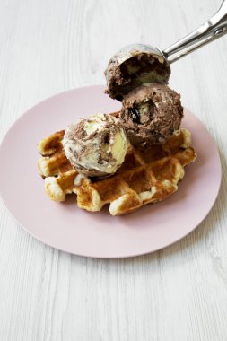 Beyaz ahşap arka plan, yan görünüm üzerinde pembe plaka üzerinde limon-çikolata dondurma ile geleneksel Belçika waffle. Portre. 