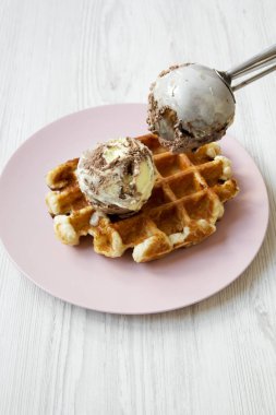 Beyaz ahşap arka plan, yan görünüm üzerinde pembe plaka üzerinde limon-çikolata dondurma ile geleneksel Belçika waffle. Yakın çekim. 