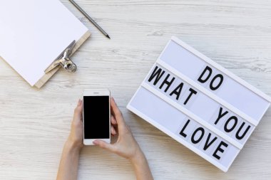 Telefon ile boş perde, üstten görünüm tutan eller. Pano, kalem ve modern yönetim kurulu üzerinde kelime 'ne aşk yapmak' ile çalışma alanı. Beyaz ahşap arka plan. Yukarıdan, düz-lay, tepegöz. 