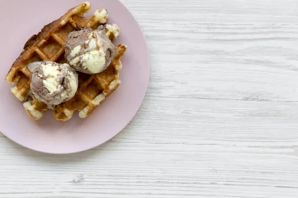 Beyaz ahşap arka plan, üstten görünüm üzerinde pembe plaka üzerinde dondurma ile geleneksel Belçika waffle. Kopya alanı.