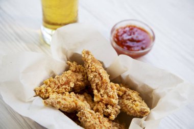 Kızarmış tavuk sosu ve soğuk bira, yan görünüm kutusu parmaklarda. Yakın çekim.