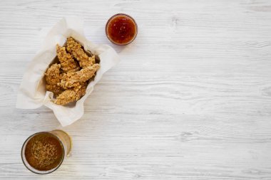 Kızarmış tavuk sosu ve soğuk bira, üstten görünüm kutusunda şeritler. Düz, tepegöz, yukarıdan yatıyordu. Kopya alanı.