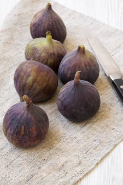 Beyaz ahşap arka plan, yan görünüm üzerinde kumaş üzerine bıçakla taze incir.