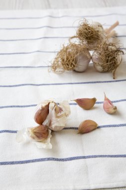 Diş sarımsak, sarımsak ampuller çizgili beyaz ahşap arka plan, yan görünüm peçete üzerinde. 