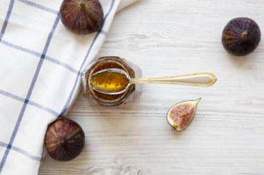 Beyaz ahşap masa, havai görünümü üzerinde taze incir ve incir reçeli cam kavanoz. Yukarıdan, ana sayfa görünümü.