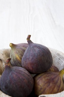 Beyaz ahşap yüzey, yan görünüm üzerinde bir kapta taze incir. Yakın çekim. Metin için yer.