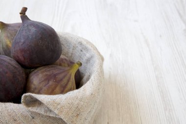 Beyaz ahşap yüzey, yan görünüm üzerinde bir kapta taze incir. Yakın çekim. Kopya alanı.