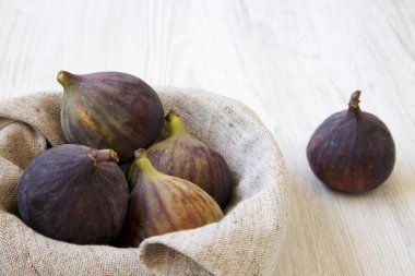 Beyaz ahşap yüzey, yan görünüm üzerinde bir kapta taze incir. Yakın çekim.