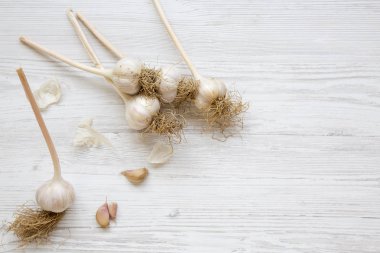 Beyaz ahşap yüzeyde sarımsak, yukarıdan görüntüleyin. Üstten görünüm, ek yükü. Metin için yer.