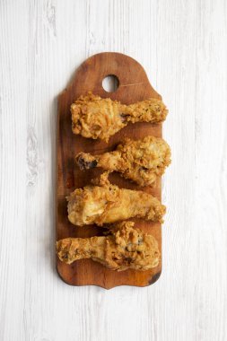 Beyaz ahşap yüzey, en iyi görünümü üzerinde ahşap tahta üzerinde kızarmış tavuk budu. Tepegöz, lay, yukarıdan düz. Portre.