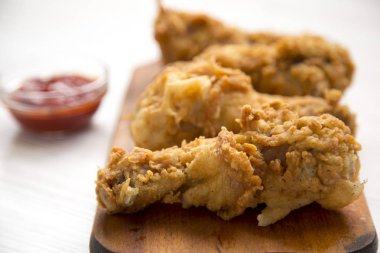 Beyaz ahşap yüzey, yan görünüm üzerinde ahşap tahta üzerinde soslu kızarmış tavuk sopaları. Yakın çekim.