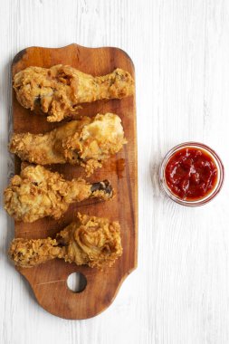 Beyaz ahşap yüzey, en iyi görünümü üzerinde ahşap tahta üzerinde soslu kızarmış tavuk sopaları. Tepegöz, yukarıdan lay, düz. 