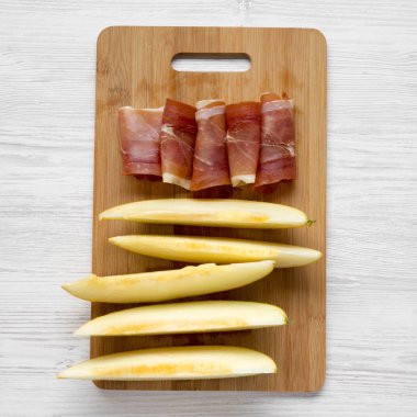 Kavun dilimleri ve prosciutto Bambu tahta üzerinde beyaz ahşap arka plan, havai görünümü üzerinde. Portre.