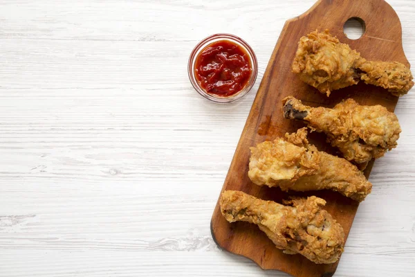 Beyaz ahşap yüzey, en iyi görünümü üzerinde ahşap tahta üzerinde soslu kızarmış tavuk sopaları. Tepegöz, lay, yukarıdan düz. Kopya alanı.