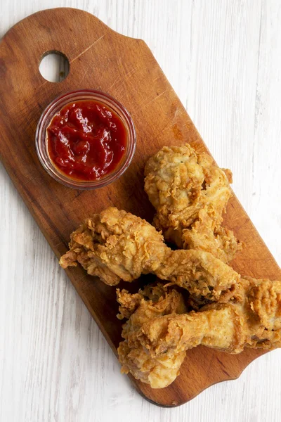 Beyaz ahşap yüzey, en iyi görünümü üzerinde ahşap tahta üzerinde soslu kızarmış tavuk sopaları. Tepegöz, yukarıdan lay, düz. 