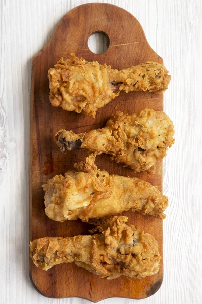 Beyaz ahşap arka plan, üstten görünüm üzerinde ahşap tahta üzerinde kızarmış tavuk sopaları. Tepegöz, lay, yukarıdan düz. Yakın çekim.