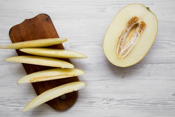 Kavun rustik ahşap tahta üzerinde beyaz ahşap yüzey, en iyi görünümü dilimlenmiş. Düz, tepegöz, yukarıdan yatıyordu.