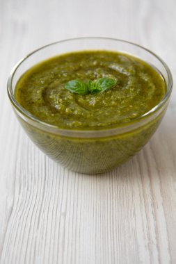 Beyaz ahşap yüzey, yan görünüm taze yapılmış fesleğen pesto kase. Yakın çekim.