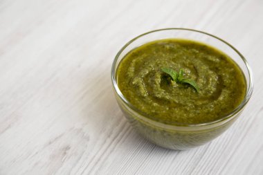 Beyaz ahşap yüzey, yan görünüm taze yapılmış fesleğen pesto kase. Portre. Kopya alanı.