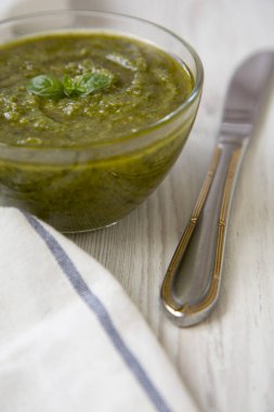 Taze yapılmış fesleğen pesto ve beyaz ahşap masa, yan görünüm bıçakta kase. Yakın çekim. 