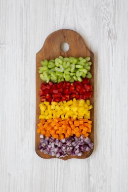 Beyaz ahşap masa, havai görünümü üzerinde kesme tahtası üzerinde düzenlenmiş kıyılmış taze sebzeler (havuç, kereviz, kırmızı soğan, renkli biber). Yukarıdan, üstten görünüm düz lay. 