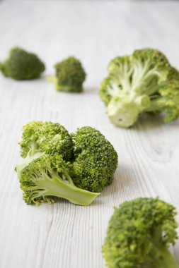 Beyaz ahşap yüzey, yan görünüm üzerinde çiğ brokoli. Seçici odak.