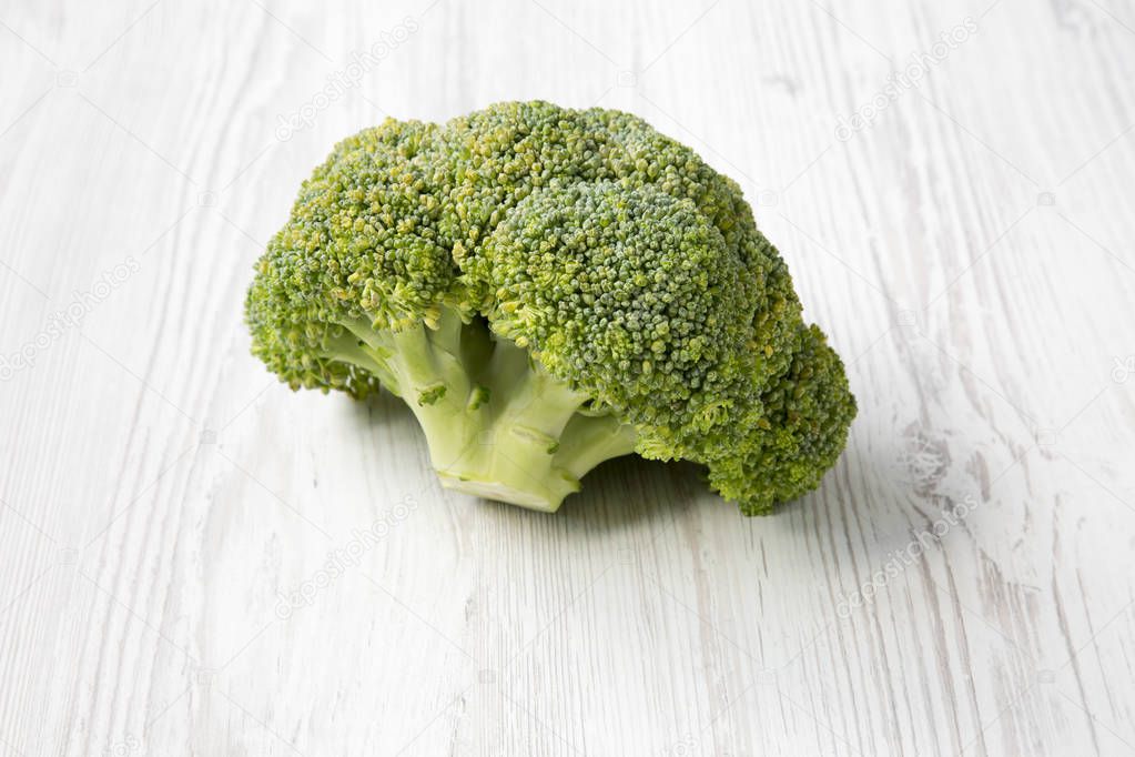 Raw broccoli on white wooden table, side view.