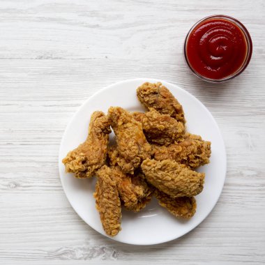 Beyaz ahşap arka plan, havai görünümü üzerine ketçap ile yuvarlak beyaz tabakta tavuk kanatları. Yukarıdan, yatıyordu, en iyi görünüm düz. Yakın çekim.